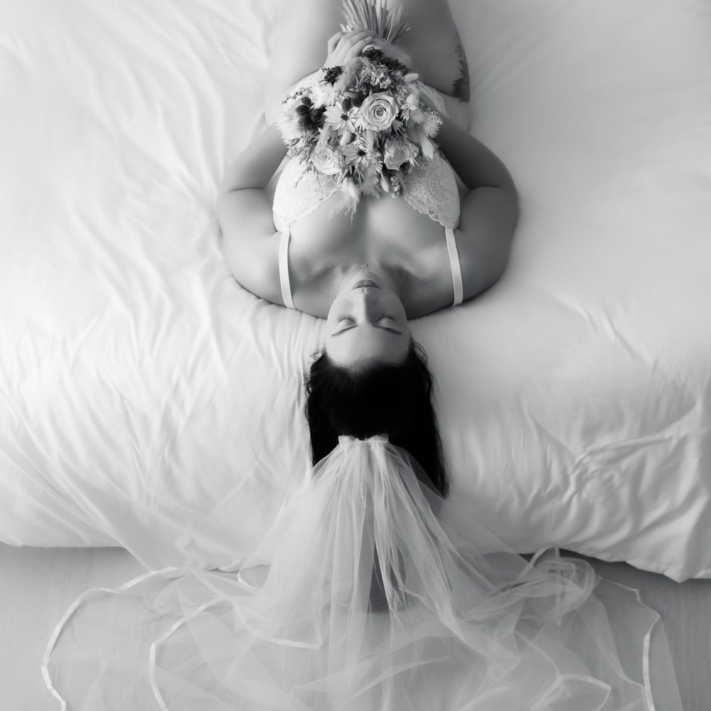 bridal boudoir shoot met bruidsboeket, witte lingerie en sluier